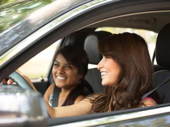 A woman driving a car with another woman in the passenger seat.