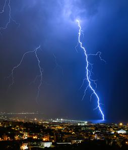 lightning bolts across the sky above a city at night