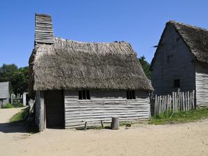 a dirt road with going past a small house made of wood