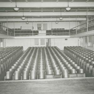 A large space with a balcony. Many theater chairs face a stage.
