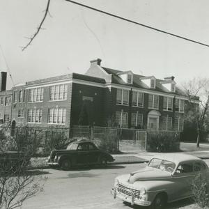 A large, well-kept school building with a fenced yard and a neatly mowed lawn.