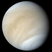 A photo of the planet Venus from space. It is covered by large, swirling clouds that are tan, yellowish, and white.