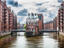 There are many tall buildings along a river. The buildings are close together.