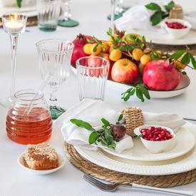a table set with honey, apples, and pomegranates