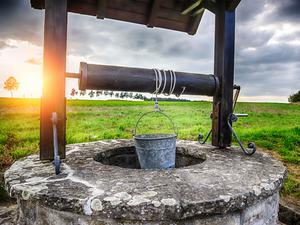 a color photo of a hole in the ground with a bucket hanging over it
