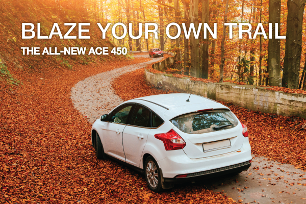 A car winds through a forest road strewn with autumn leaves. The text says, "Blaze your own trail. The all-new Ace 450."